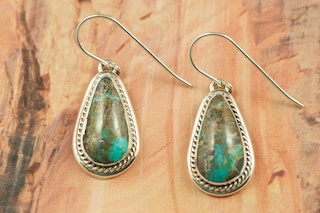 Genuine Sunnyside Turquoise set in Sterling Silver French Wire Earrings. The matrix on this rare stone is outstanding. The Sunnyside mine is located in northern Nevada near the town of Tuscarora in the Tuscarora mountain range. The mine is no longer in operation as it has become part of a gold mining operation and a privately owned ranch. The Sunnyside mine was mined mostly in the 70's. You won't find much of this great turquoise around anymore except for old stashes. Created by Navajo Artist Arkie Nelson. Signed by the artist. 

